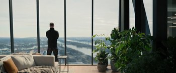 Movie still from “Extraction II” (2023), directed by Sam Hargrave – A man standing in front of a window overlooking a river; Wide shot, Low angle