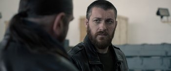 Movie still from “Extraction II” (2023), directed by Sam Hargrave – A man in a leather jacket looking at another man in a leather jacket; Close Up shot, Over the shoulder angle