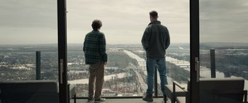 Movie still from “Extraction II” (2023), directed by Sam Hargrave – Two men look out over a city from the top of a skyscraper; Wide shot, Over the shoulder angle