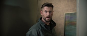 Movie still from “Extraction II” (2023), directed by Sam Hargrave – A person wearing a jacket and looking angry; Close Up shot, Over the shoulder angle