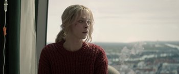 Movie still from “Extraction II” (2023), directed by Sam Hargrave – A woman with blonde hair wearing a red sweater looking off into the distance; Close Up shot, Over the shoulder angle