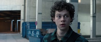 Movie still from “Extraction II” (2023), directed by Sam Hargrave – A young man with curly black hair wearing a plaid shirt; Close Up shot, Low angle