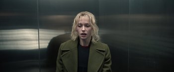 Movie still from “Extraction II” (2023), directed by Sam Hargrave – A woman in a green coat standing next to an elevator; Close Up shot, Low angle
