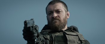 Movie still from “Extraction II” (2023), directed by Sam Hargrave – A person holding a gun; Close Up shot, Low angle