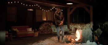 Movie still from “Extraction II” (2023), directed by Sam Hargrave – A man standing in front of a pile of wood; Wide shot, Over the shoulder angle