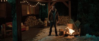 Movie still from “Extraction II” (2023), directed by Sam Hargrave – A man standing in front of a pile of wood; Wide shot, Low angle