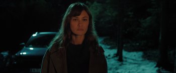 Movie still from “Extraction II” (2023), directed by Sam Hargrave – A woman standing in the dark in front of a forest; Close Up shot, Over the shoulder angle