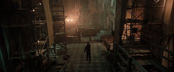 Movie still from “Extraction II” (2023), directed by Sam Hargrave – A man standing in a room with scaffolding around it; Extreme Wide shot, High angle