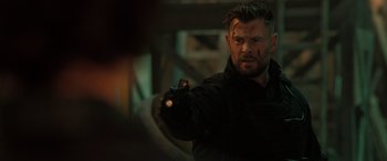 Movie still from “Extraction II” (2023), directed by Sam Hargrave – A person holding a gun; Close Up shot, Over the shoulder angle