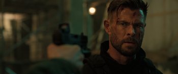 Movie still from “Extraction II” (2023), directed by Sam Hargrave – A person holding a gun; Close Up shot, Over the shoulder angle