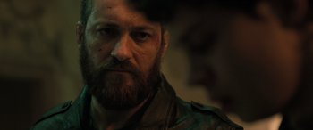 Movie still from “Extraction II” (2023), directed by Sam Hargrave – A person with a beard; Close Up shot, Over the shoulder angle