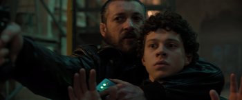 Movie still from “Extraction II” (2023), directed by Sam Hargrave – A man and a young boy holding a cell phone; Close Up shot, Low angle