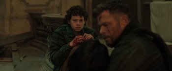 Movie still from “Extraction II” (2023), directed by Sam Hargrave – A young man is sitting on a chair with blood on his face; Medium shot, High angle