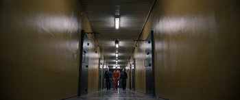 Movie still from “Extraction II” (2023), directed by Sam Hargrave – A group of men in orange suits walking down a hall way; Extreme Wide shot, High angle