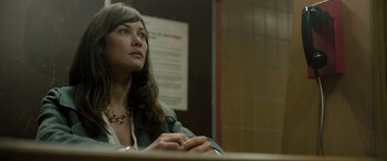Movie still from “Extraction II” (2023), directed by Sam Hargrave – A woman sitting in front of a table looking up; Close Up shot, Over the shoulder angle