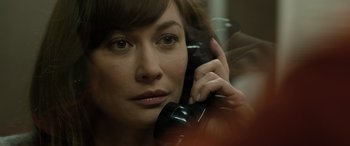 Movie still from “Extraction II” (2023), directed by Sam Hargrave – A woman is talking on a phone while looking at the camera; Close Up shot, Over the shoulder angle