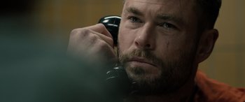 Movie still from “Extraction II” (2023), directed by Sam Hargrave – A person talking on a phone; Close Up shot, Over the shoulder angle