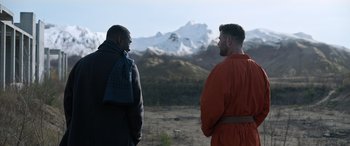Movie still from “Extraction II” (2023), directed by Sam Hargrave – Two men standing in front of a snowy mountain; Medium shot, Over the shoulder angle