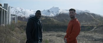 Movie still from “Extraction II” (2023), directed by Sam Hargrave – Two men standing next to each other in front of a snowy mountain; Medium shot, Low angle
