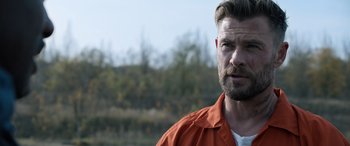 Movie still from “Extraction II” (2023), directed by Sam Hargrave – A person wearing an orange shirt; Close Up shot, Over the shoulder angle