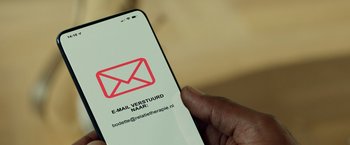 Movie still from “F*ck Love Too” (2022), directed by Appie Boudellah – A hand holding a smart phone with an e - mail sign on the screen; Extreme Close Up shot, Overhead angle