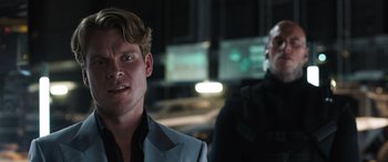 Movie still from “F9: The Fast Saga” (2021), directed by Justin Lin – A man in a suit standing next to another man in a suit; Close Up shot, Over the shoulder angle