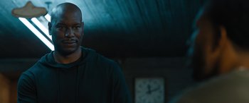 Movie still from “F9: The Fast Saga” (2021), directed by Justin Lin – A man standing in front of a clock in a dark room; Close Up shot, Over the shoulder angle