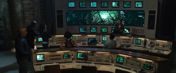 Movie still from “F9: The Fast Saga” (2021), directed by Justin Lin – A group of people sitting in front of a large screen; Wide shot, High angle