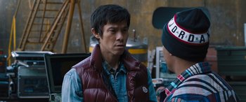 Movie still from “F9: The Fast Saga” (2021), directed by Justin Lin – A man wearing a red vest talking to another man; Close Up shot, Over the shoulder angle