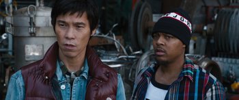 Movie still from “F9: The Fast Saga” (2021), directed by Justin Lin – Two young men standing next to each other in front of a motorcycle; Close Up shot, Low angle