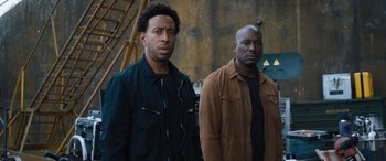 Movie still from “F9: The Fast Saga” (2021), directed by Justin Lin – A couple of men standing next to each other; Medium shot, Low angle