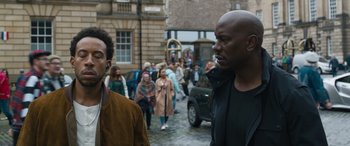 Movie still from “F9: The Fast Saga” (2021), directed by Justin Lin – Two men walking down the street in a crowd; Medium shot, Over the shoulder angle