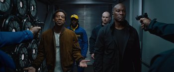 Movie still from “F9: The Fast Saga” (2021), directed by Justin Lin – A group of men standing next to each other in a building; Medium shot, Low angle