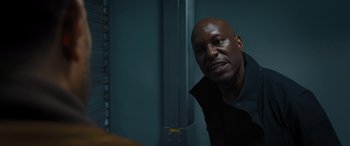 Movie still from “F9: The Fast Saga” (2021), directed by Justin Lin – A man with a black shirt is looking at the camera; Close Up shot, Over the shoulder angle