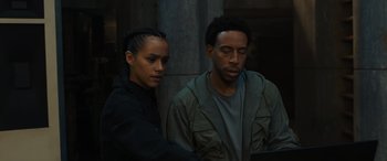 Movie still from “F9: The Fast Saga” (2021), directed by Justin Lin – A man and a woman looking at something on a computer screen; Medium shot, Low angle
