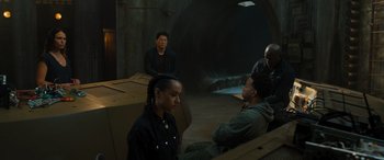 Movie still from “F9: The Fast Saga” (2021), directed by Justin Lin – A group of people sitting in a dark room; Wide shot, High angle