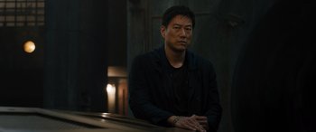 Movie still from “F9: The Fast Saga” (2021), directed by Justin Lin – A man sitting at a table in front of a candle; Medium shot, Low angle