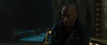 Movie still from “F9: The Fast Saga” (2021), directed by Justin Lin – A man in a black jacket is sitting down; Close Up shot, Over the shoulder angle