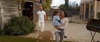 Movie still from “F9: The Fast Saga” (2021), directed by Justin Lin – A woman holding a child while standing next to a man; Wide shot, High angle