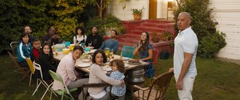Movie still from “F9: The Fast Saga” (2021), directed by Justin Lin – A group of people sitting at a table with food; Wide shot, High angle
