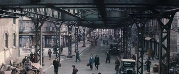 Movie still from “Fantastic Beasts and Where to Find Them” (2016), directed by David Yates – A group of people walking on a street near a train station; Extreme Wide shot, High angle