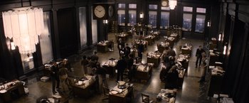 Movie still from “Fantastic Beasts and Where to Find Them” (2016), directed by David Yates – A group of people standing around tables in a large room; Extreme Wide shot, High angle
