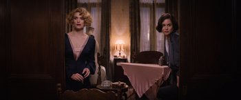 Movie still from “Fantastic Beasts and Where to Find Them” (2016), directed by David Yates – Two women sitting at a table in front of a lamp; Medium shot, High angle