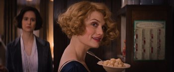 Movie still from “Fantastic Beasts and Where to Find Them” (2016), directed by David Yates – A woman is holding a bowl of food and smiling; Close Up shot, Over the shoulder angle