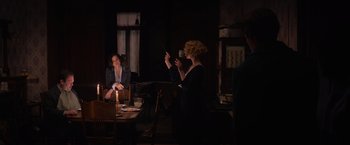 Movie still from “Fantastic Beasts and Where to Find Them” (2016), directed by David Yates – Two women are sitting at a table in a dark room; Wide shot, Over the shoulder angle