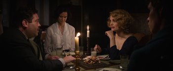 Movie still from “Fantastic Beasts and Where to Find Them” (2016), directed by David Yates – A group of people sitting at a table with candles; Medium shot, Over the shoulder angle