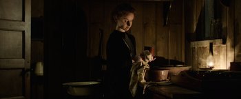 Movie still from “Fantastic Beasts and Where to Find Them” (2016), directed by David Yates – A woman standing in front of a sink in a dark room; Medium shot, Low angle