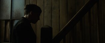 A man standing on top of a wooden stair railing next to a railing