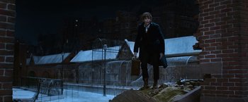 Movie still from “Fantastic Beasts and Where to Find Them” (2016), directed by David Yates – A man holding a briefcase while standing on top of a hill; Wide shot, Low angle
