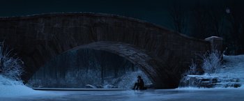 Movie still from “Fantastic Beasts and Where to Find Them” (2016), directed by David Yates – A person sitting on the ground under a bridge at night; Extreme Wide shot, High angle